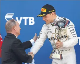  ??  ?? Valtteri Bottas receives the Russian Grand Prix trophy from President Putin.