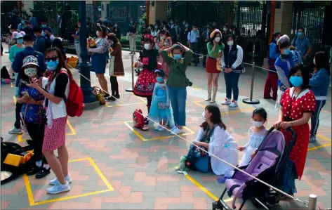  ?? AP PHOTO/SAM MCNEIL ?? Visitors, wearing face masks, wait to enter the Disneyland theme park in Shanghai as it reopened, Monday.