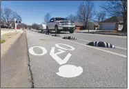  ?? NWA Democrat-Gazette/FLIP PUTTHOFF ?? Vehicles move Saturday along Dick Smith Street in Springdale between barriers installed to create bike lanes on each side of the street.