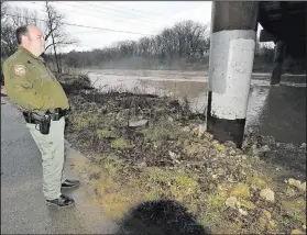  ?? NWA Democrat-Gazette/FLIP PUTTHOFF ?? Clayton Hungate, a wildlife officer with the Arkansas Game and Fish Commission, watches Saturday the White River flows swiftly under the Arkansas 45 bridge at Goshen. The river, a tributary of Beaver Lake, was bank-full Saturday in the wake of more rain.