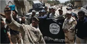  ?? (Reuters) ?? IRAQI ARMY soldiers pose for a photo with an ISIS flag, claimed after fighting in western Mosul last month.