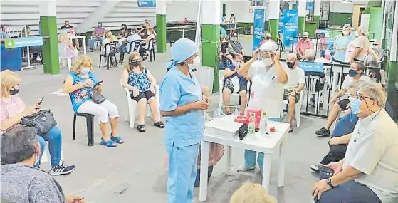  ??  ?? Espera. Vecinos aguardan los 20 minutos de rigor tras recibir la vacuna en la posta instalada bajo una tribuna de la cancha de Banfield.