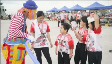  ??  ?? A clown entertains children on the sideline of the event.