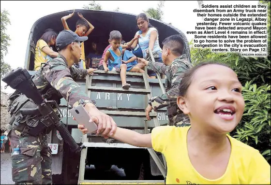  ?? KRIZJOHN ROSALES ?? Soldiers assist children as they disembark from an Army truck near their homes outside the extended danger zone in Legazpi, Albay yesterday. Fewer volcanic quakes have been detected around Mayon even as Alert Level 4 remains in effect. Some residents...