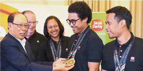  ?? — EBBY SAIFUL / The Star ?? Precious
collection: Yayasan Sime Darby chairman Tun Musa Hitam (left) admiring Mohd Fadhil Mohd Zonis’ medals won at the recent KL SEA Games after announcing support for six track cyclists at the Sime Darby Convention Centre in Kuala Lumpur...