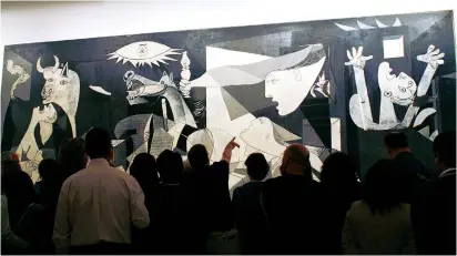  ?? (Susana Vera/Reuters) ?? VISITORS STUDY Spanish artist Pablo Picasso’s masterpiec­e ‘Guernica,’ at Madrid’s Reina Sofia National Museum of Art. The painting is the classic icon of communal suffering and pain.