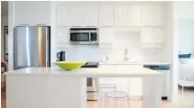  ??  ?? A white-on-white European-style kitchen integrates seamlessly into the decor, offering the eye a greater sense of space in the open-concept layout.