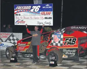  ?? RICH KEPNER - FOR MEDIANEWS GROUP ?? Jeff Strunk raises the winner’s check after winning the Freedom 76 on Sept. 19 at Grandview Speedway.