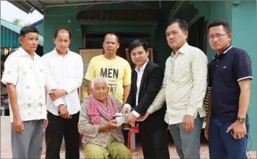  ?? FRESH NEWS ?? Fresh News CEO Lim Cheavutha (in suit) gives money to the late political analyst Kem Ley’s mother that was donated by Prime Minister Hun Sen to pay for a stupa to honour the slain government critic.