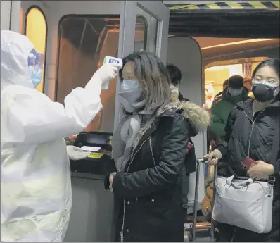  ?? PICTURE: AP ?? VIRUS SIGNS: Health officials in Beijing check body temperatur­es of passengers arriving from Wuhan.