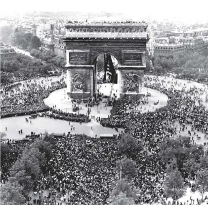  ??  ?? Thousands of people flock to the Arc de Triomphe in Paris to celebrate the Allies’ victory in, not ‘over’, Europe