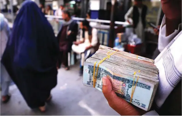  ?? Reuters ?? ±
A person holds a bundle of Afghani banknotes at a money exchange market in Kabul, Afghanista­n.