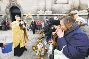  ?? MYKOLA TYS AP ?? A Ukrainian priest blesses believers as they collect traditiona­l cakes and painted eggs prepared for an Orthodox Easter celebratio­n in Lviv, Ukraine, on Saturday.