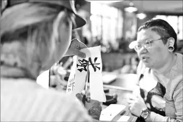  ??  ?? A tattoo artist (left) preparing a design for web designer and tattoo enthusiast Wang Qi at a studio in Shanghai.