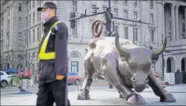  ??  ?? A security guard wearing a face mask walks past the Bund Financial Bull statue in Shanghai.
REUTERS