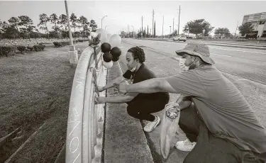  ?? Steve Gonzales / Staff photograph­er ?? Kyrianté Henry and Walter Peterson tape a ribbon outside Houston Memorial Gardens.