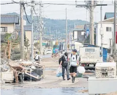  ??  ?? WEEKEND CLEANUP: Local residents walk in a flooded area in Mabi town in Kurashiki, Okayama Prefecture, Japan.