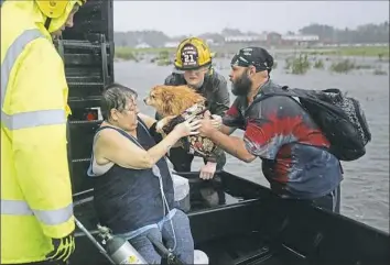  ?? Chip Somodevill­a/Getty Images ?? Rescue workers from Township No. 7 Fire Department and volunteers from the Civilian Crisis Response Team help rescue a woman and her dog from their flooded home during Hurricane Florence on Friday in James City, N.C.