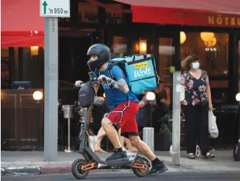  ?? (Amir Cohen/Reuters) ?? A COURIER rides a scooter as he delivers an order from a restaurant in Tel Aviv last week.