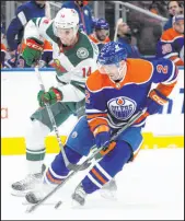  ?? Jason Franson The Associated Press ?? Oilers defenseman Evan Bouchard controls the puck ahead of Wild center Joel Eriksson Ek during Edmonton’s 4-3 victory Friday night at Rogers Place.