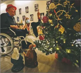  ??  ?? Palmiro Tami looks at a Christmas tree with Madaschi before talking via video call with a “Santa’s Grandchild­ren” donor.