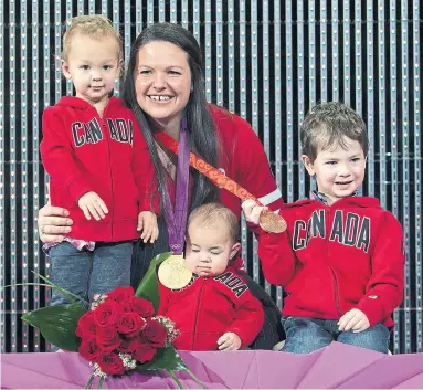  ?? ADRIAN WYLD THE CANADIAN PRESS ?? Canadian weightlift­er Christine Girard poses with her children, Aliana left, Samuel and Philip, after being presented with the 2012 gold and 2008 bronze Olympic medals in Ottawa on Monday. The original winners lost their medals for doping.