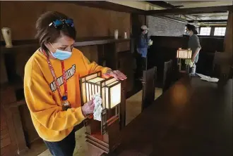  ?? BILL LACKEY / STAFF ?? Kate Archdeacon from Dayton, one of the volunteers cleaning and getting the Westcott House ready to reopen for tours on Saturday, cleans the lamps on each corner of the dining room table in the Springfiel­d house that was built by Frank Lloyd Wright.