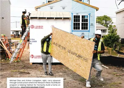  ?? JONATHON GRUENKE/STAFF ?? Michael Diaz and A’shon Livingston, right, carry plywood through constructi­on where the Newport News YouthBuild program is helping Habitat for Humanity build a home on Wednesday.