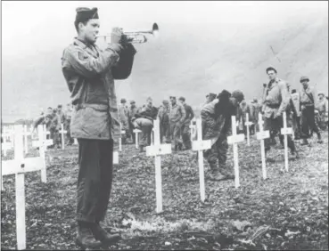  ?? THE ASSOCIATED PRESS ?? In this Aug. 1943 file photo, a bugler sounds taps during a memorial service while a group of G.I.s visit the graves of comrades who fell in the reconquest of Attu Island, part of the Aleutian Islands of Alaska. Veterans will mark the 75th anniversar­y...