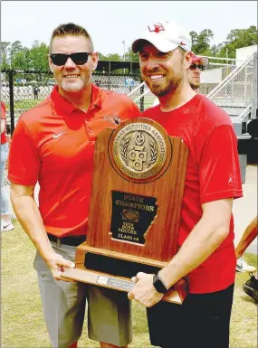  ?? MARK HUMPHREY ENTERPRISE-LEADER ?? Farmington athletic director Beau Thompson (left) poses with interim head boys soccer coach Josh Fonville with the Class 4A State championsh­ip trophy in the aftermath of Farmington’s 4-3 victory over Clarksvill­e in Saturday’s state finals played at Everett Field at the Benton Athletic Complex. Thompson persuaded Fonville to take over the program in December after an unexpected coaching vacancy occurred.