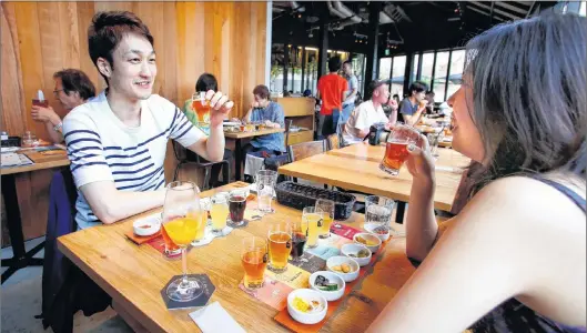  ?? AP PHOTO ?? Takuya Iwata (left) and Mai Kamii drink beer at Spring Valley Brewery in Tokyo.