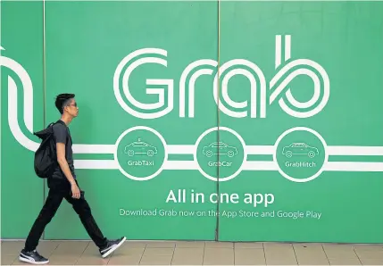  ?? REUTERS ?? A man walks past a Grab office in Singapore.