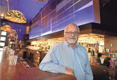  ?? MIKE DE SISTI/MILWAUKEE JOURNAL SENTINEL ?? Von Trier owner John Sidoff stands near an uncovered midcentury mural at the bar on N. Farewell Ave. in Milwaukee. The mural has been hidden behind a German mural for several decades. It is meant to be viewed under black lights, which were installed...