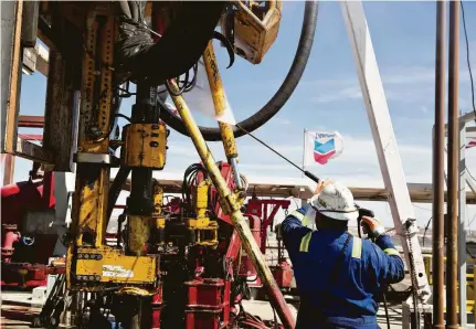  ?? Daniel Acker / Bloomberg ?? A Nabors Industries roughneck uses a power washer to clean the drilling floor of a rig drilling for Chevron Corp. in the Permian Basin near Midland this month. Permian production crossed the 3-million-barrel-a-day mark last month.