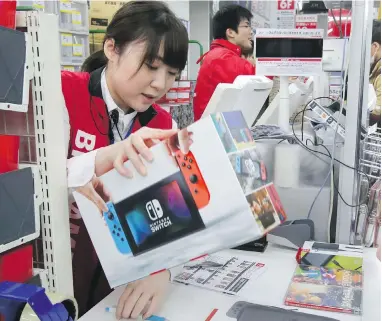  ?? AP ?? A Bic Camera clerk sells a Nintendo Switch in Tokyo Friday, where gamers lined up to buy the new console.