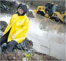  ?? ASHLEY FRASER ?? Jo-Anne Poulin sits on the levee dike that is holding a flood of water back from her home and her neighbours’ homes. Poulin is thankful her neighbour, Claude Proulx, helped to build the dirt wall.