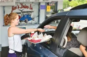  ?? BOB WOJCIESZAK/DAILY MAIL VIA AP, FILE ?? Jim’s Drive-In waitress Aly King delivers an order to a waiting customer at the iconic restaurant in Lewisburg, W.Va.