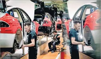  ?? David Butow For The Times ?? A WORKER is ref lected in a computer screen at Tesla’s factory in Fremont, Calif. Beginning this year, the plant will be used to produce the Model 3 electric car, at top, which will start at $35,000.