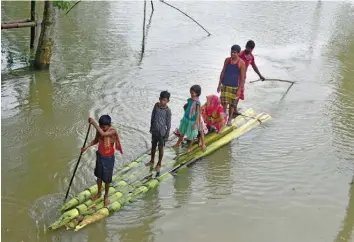  ?? — PTI ?? Locals cross a flooded area on a makeshift raft in Nagaon district of Assam on Saturday.