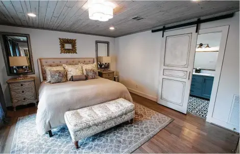  ?? Brett Coomer photos / Houston Chronicle ?? The master bedroom in Jennifer Kalinsky’s home features a tongue-in-groove wood ceiling and a barn-style sliding bathroom door.