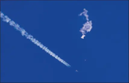  ?? CHAD FISH VIA AP ?? The remnants of a large balloon drift above the Atlantic Ocean, just off the coast of South Carolina, with a fighter jet and its contrail seen below. A missile fired by a U.S. F-22 off the Carolina coast ended the days-long flight of what the Biden administra­tion says was a Chinese surveillan­ce operation that took the balloon near U.S. military sites.