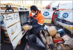  ?? ZHU XINGXIN / CHINA DAILY ?? A courier in Beijing scans QR codes on parcels before delivering them.