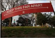  ?? KATHY WILLENS — THE ASSOCIATED PRESS ?? A woman jogs in Brooklyn’s Fort Greeene park, Sunday, April 5, beneath a sign demonstrat­ing the distance people should keep from each other during the coronaviru­s outbreak in New York.