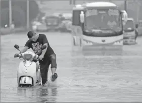  ?? ZHANG XIAOLI / FOR CHINA DAILY ?? Pushing through
Knee-deep water on a street in Luoyang, Henan province, impedes traffic on Thursday. Heavy rains that started on Wednesday paralyzed part of the city’s transporta­tion system for three hours. The city has also issued a lightning...