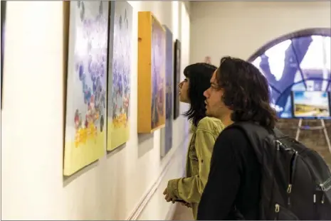  ?? VINCENT OSUNA PHOTO ?? Alexis Mendoza, 19, (left) and Luis Cota, 21, view a piece of artwork during the city of Calexico’s 110th Anniversar­y Art Exhibit held at the Carmen Durazo Cultural Arts Center on Wednesday in Calexico.