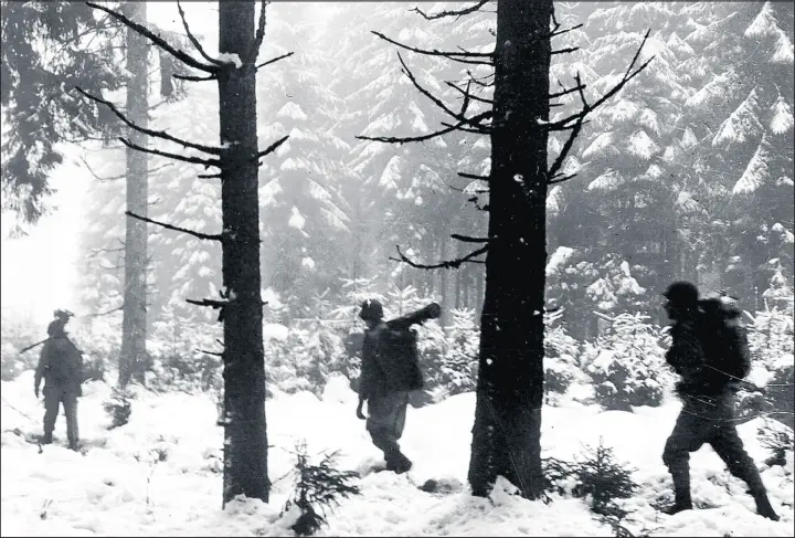  ?? ASSOCIATED PRESS ?? Infantryme­n of the U.S. First Army plod through snowy woods in Belgium’s Ardennes Forest as they advance to contact German forces at the Battle of the Bulge, December 1944.