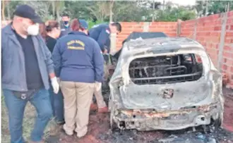  ?? ?? Policías verifican el interior del auto quemado en cuyo interior encontraro­n el cadáver calcinado.