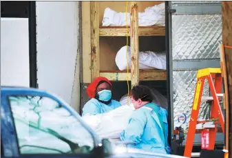  ?? LUCAS JACKSON / REUTERS ?? Healthcare workers transfer a body onto a stretcher at Kingsbrook Jewish Medical Center on Wednesday as the coronaviru­s outbreak continues in New York.