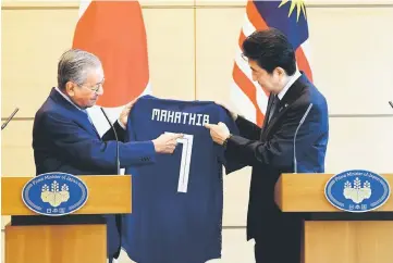  ?? — Bernama photo ?? Dr Mahathir (left) receives Japan’s football jersey number seven as memento from Abe after the press conference.