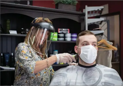  ?? The Canadian Press ?? Frank’s Barbershop owner Rosanna Petan wears a face shield as she cuts Jack Willis’s hair in Vancouver on May 19.